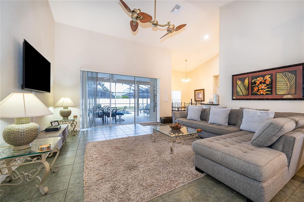 A living room features a gray sectional sofa, a glass coffee table, and a ceiling fan — 569 BURFORD CIRCLE, DAVENPORT, FL