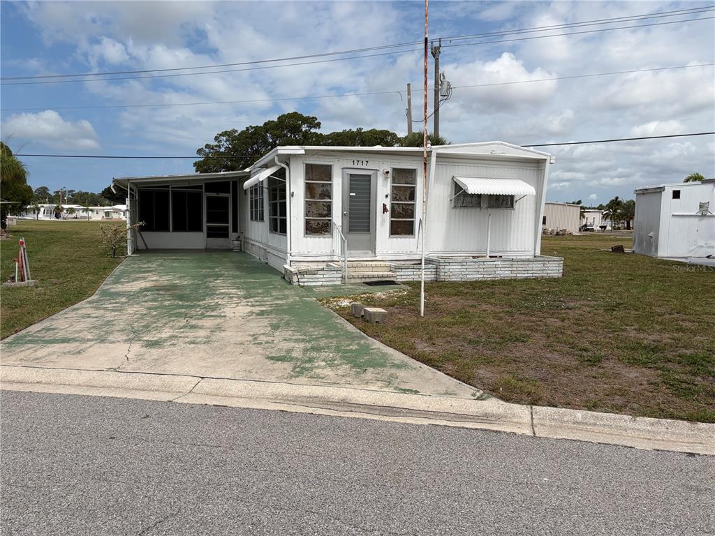 A single-story mobile home with a screened carport and a concrete driveway — 1717 PALM SPRINGS STREET, SARASOTA, FL