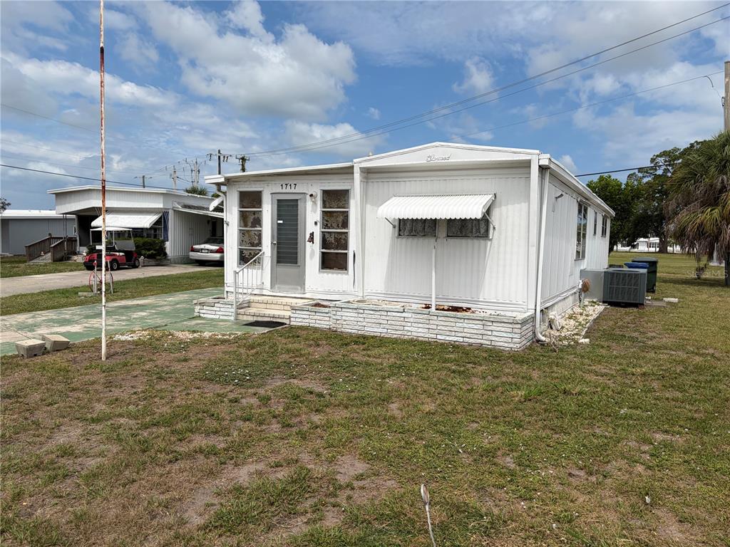 A white mobile home with a brick base and a metal awning over the window — 1717 PALM SPRINGS STREET, SARASOTA, FL
