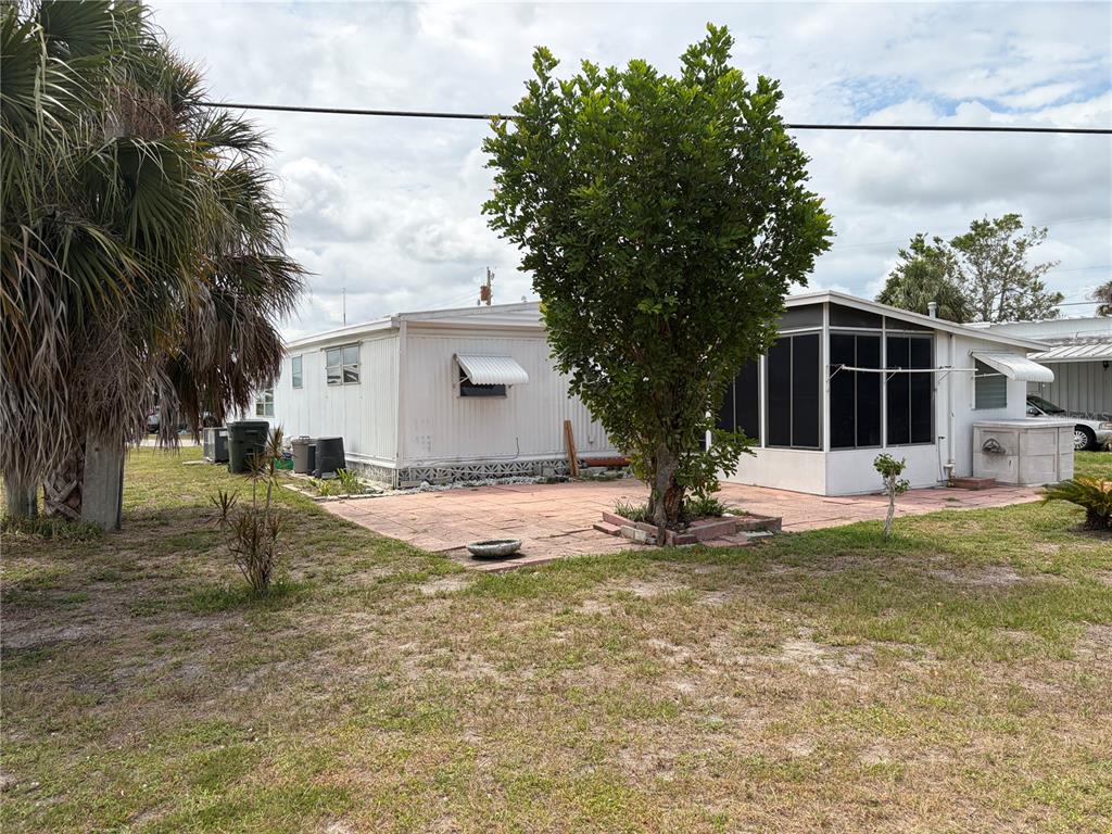 A mobile home with a screened-in porch and a paved patio area in the yard — 1717 PALM SPRINGS STREET, SARASOTA, FL