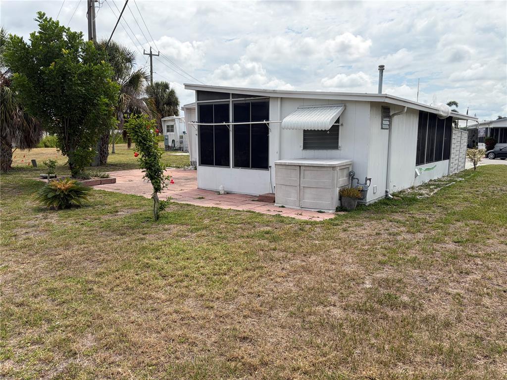A white mobile home features a screened-in porch and a paved patio area — 1717 PALM SPRINGS STREET, SARASOTA, FL
