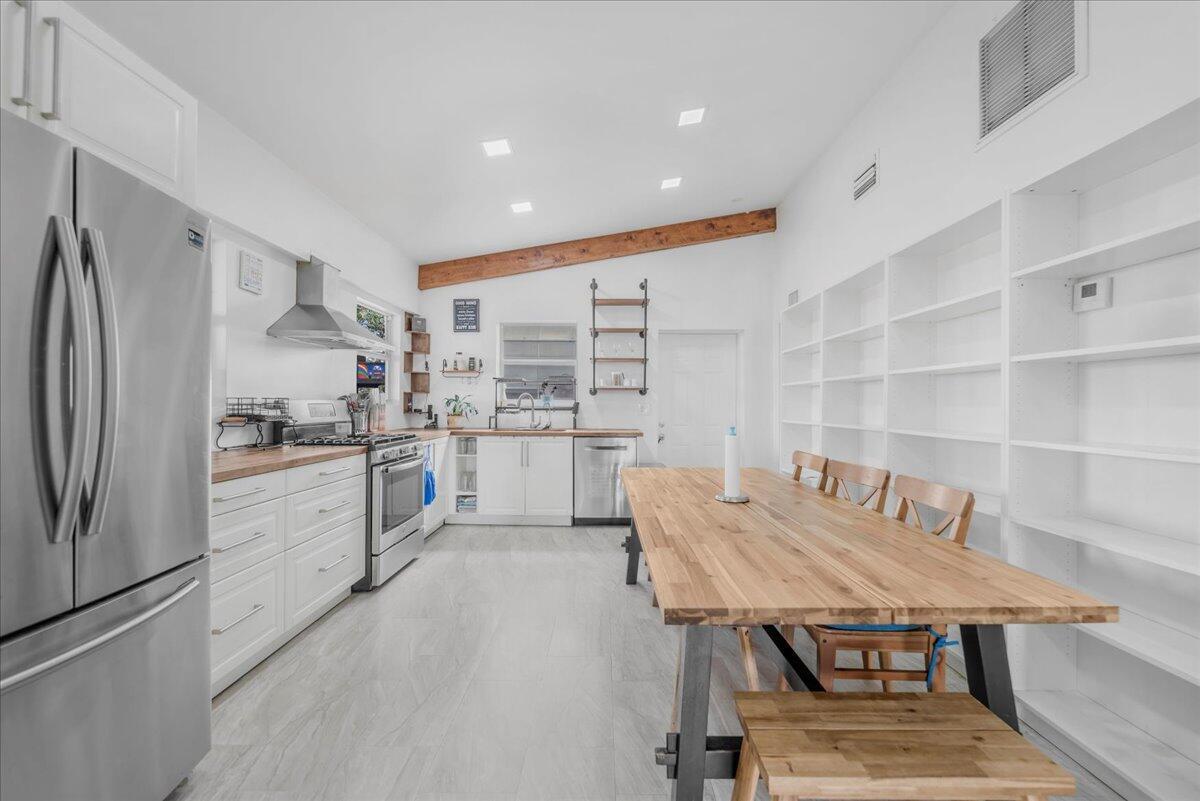 A kitchen with white cabinets, wood countertops, a large dining table, and built-in shelving — 1205 Coffey Road, Moore Haven FL 33471, MOORE HAVEN, FL
