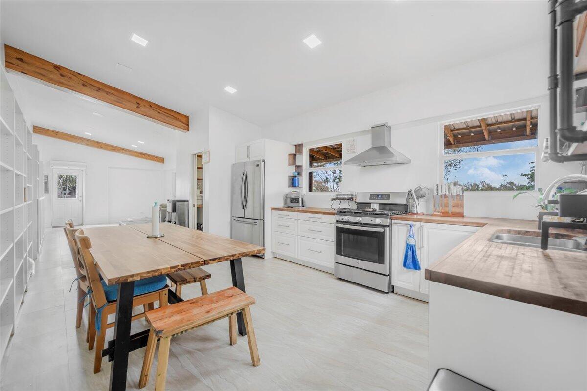 A kitchen features white cabinets, wood countertops, stainless steel appliances, and exposed ceiling beams — 1205 Coffey Road, Moore Haven FL 33471, MOORE HAVEN, FL