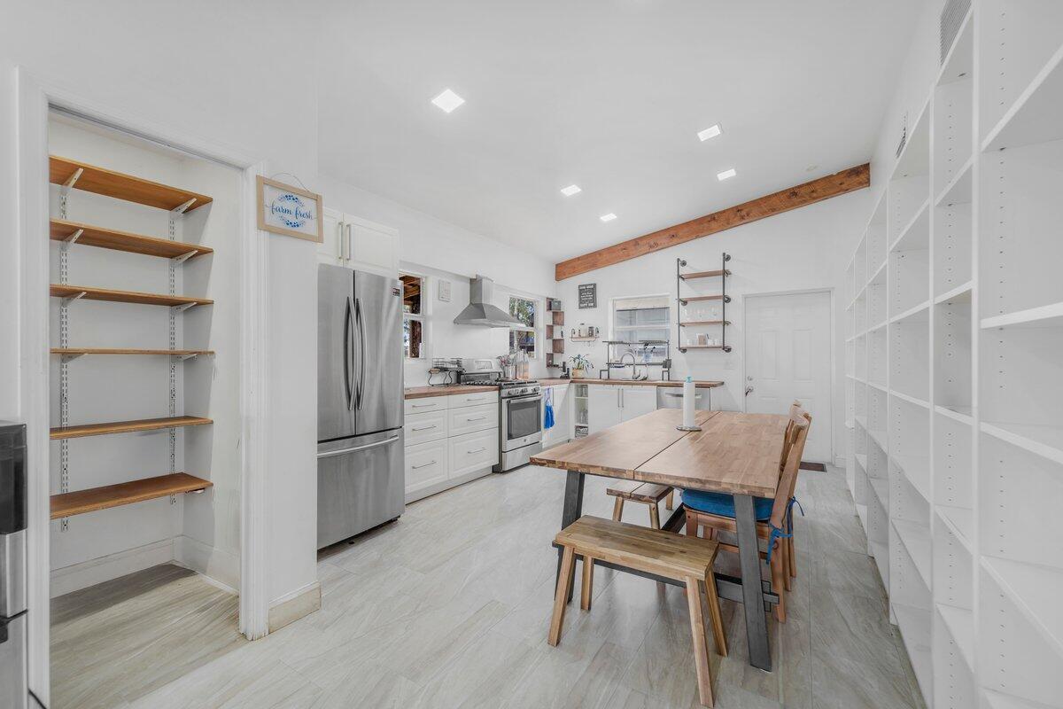 A kitchen features white cabinetry, stainless steel appliances, a wooden dining table, and open shelving — 1205 Coffey Road, Moore Haven FL 33471, MOORE HAVEN, FL