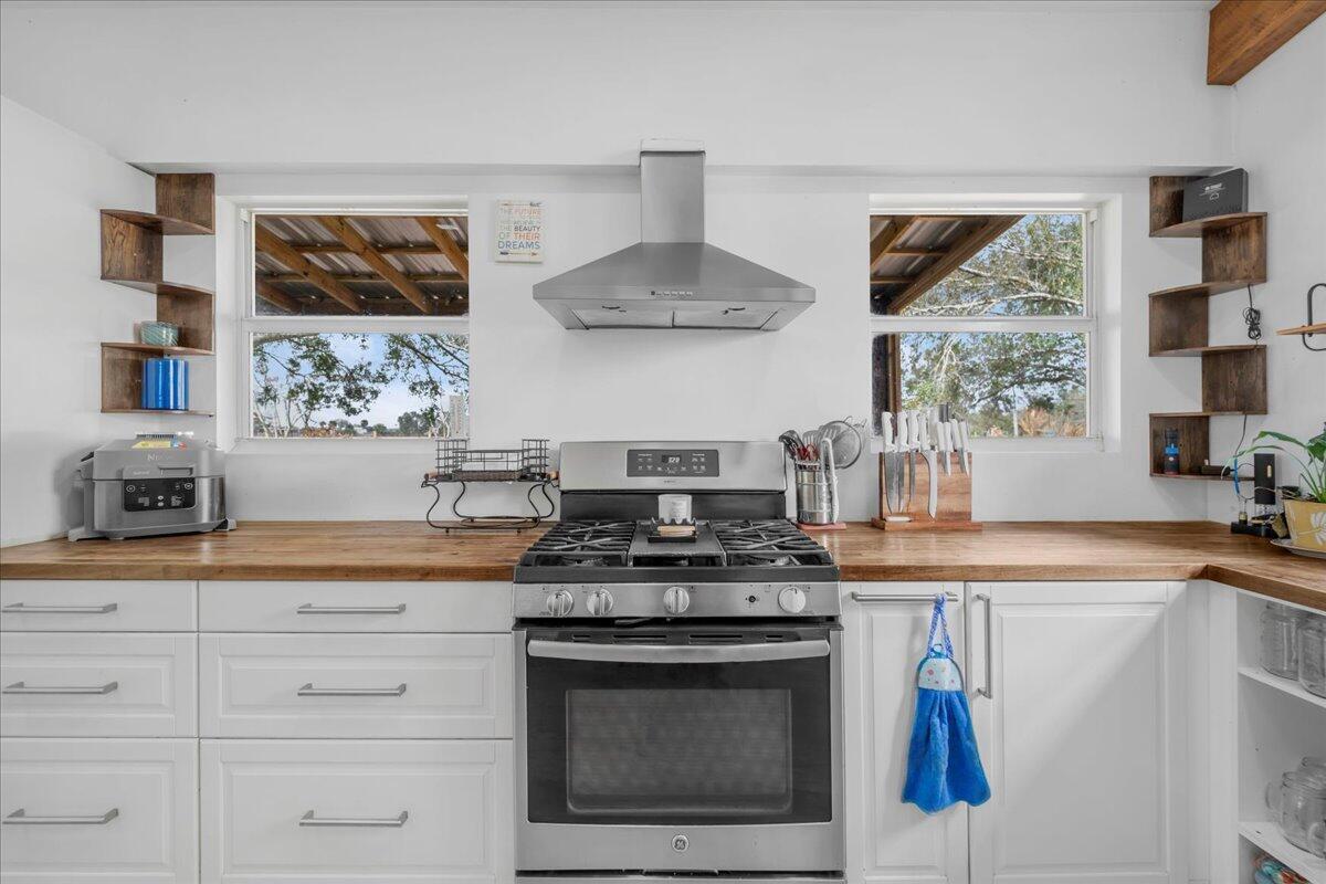 A kitchen features white cabinets, a wooden countertop, a stainless steel stove, and two windows — 1205 Coffey Road, Moore Haven FL 33471, MOORE HAVEN, FL