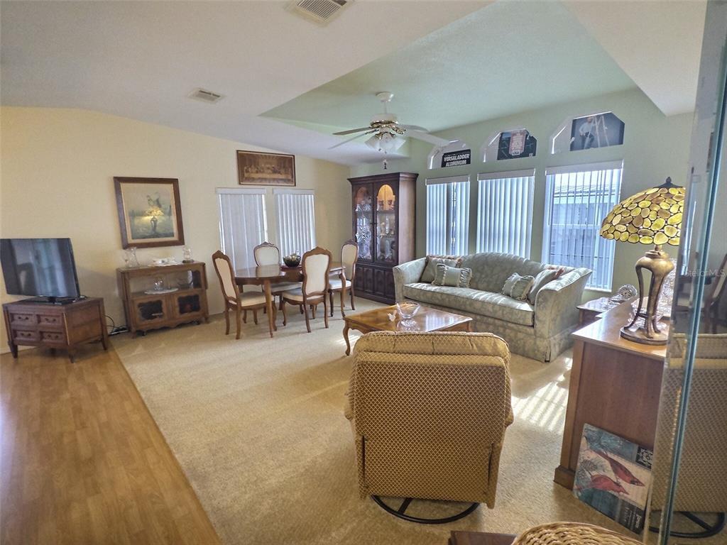 A living and dining area features carpeted flooring, a ceiling fan, and traditional wooden furniture — 136 PINDO PALM STREET W, LARGO, FL