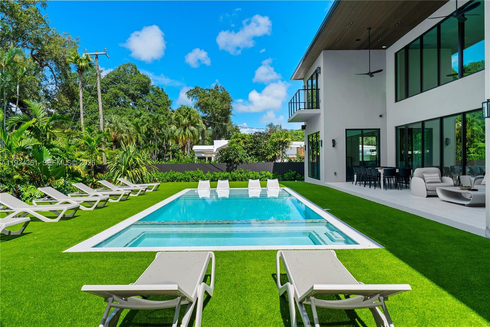 A modern two-story house features a rectangular swimming pool with lounge chairs on artificial turf — 19900 NE 21st Ct, Miami FL 33179, MIAMI, FL