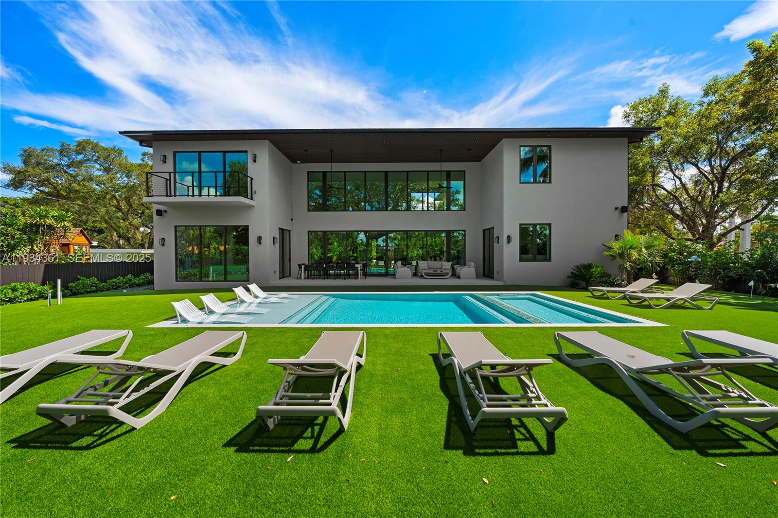 A modern two-story house features a large swimming pool and lounge chairs on a lawn — 19900 NE 21st Ct, Miami FL 33179, MIAMI, FL