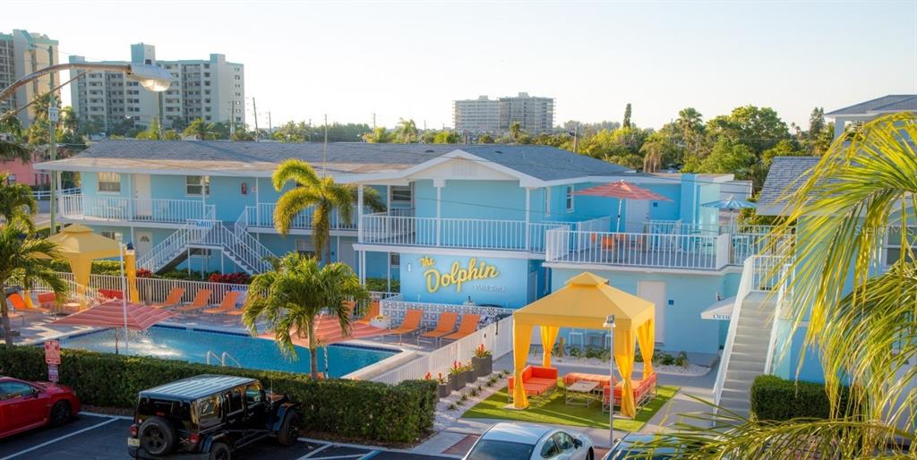 An exterior view of a blue two-story motel with a swimming pool and yellow gazebos — 6801 SUNSET WAY, ST PETE BEACH, FL