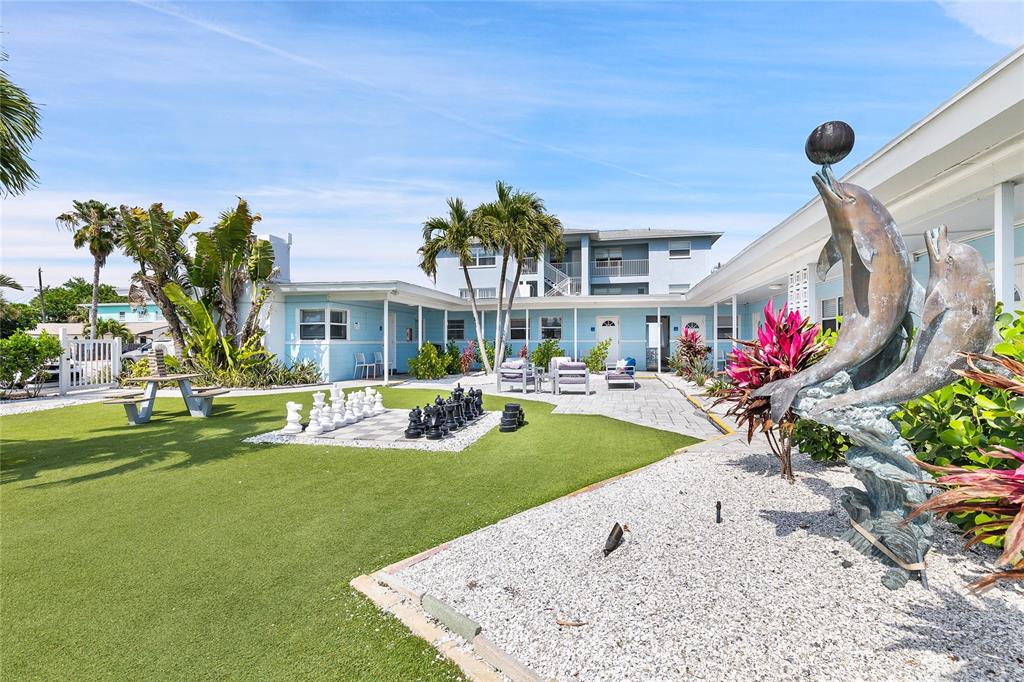 A courtyard features a giant chess set, a dolphin statue, and a blue building exterior — 6801 SUNSET WAY, ST PETE BEACH, FL