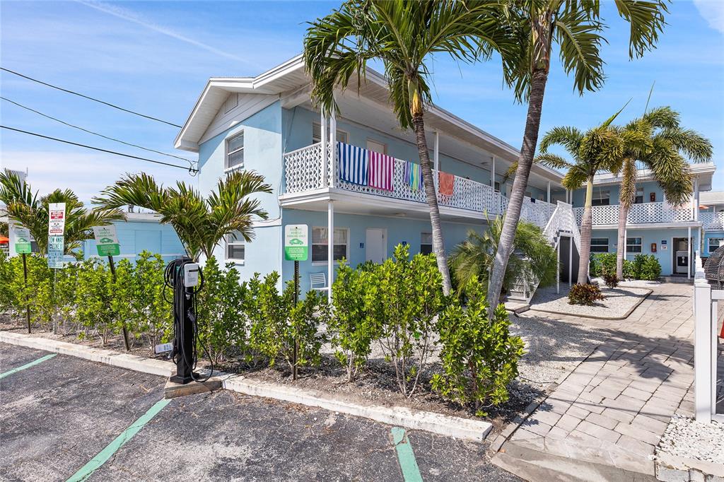 A two-story light blue apartment building with a balcony, palm trees, and a parking lot — 6801 SUNSET WAY, ST PETE BEACH, FL