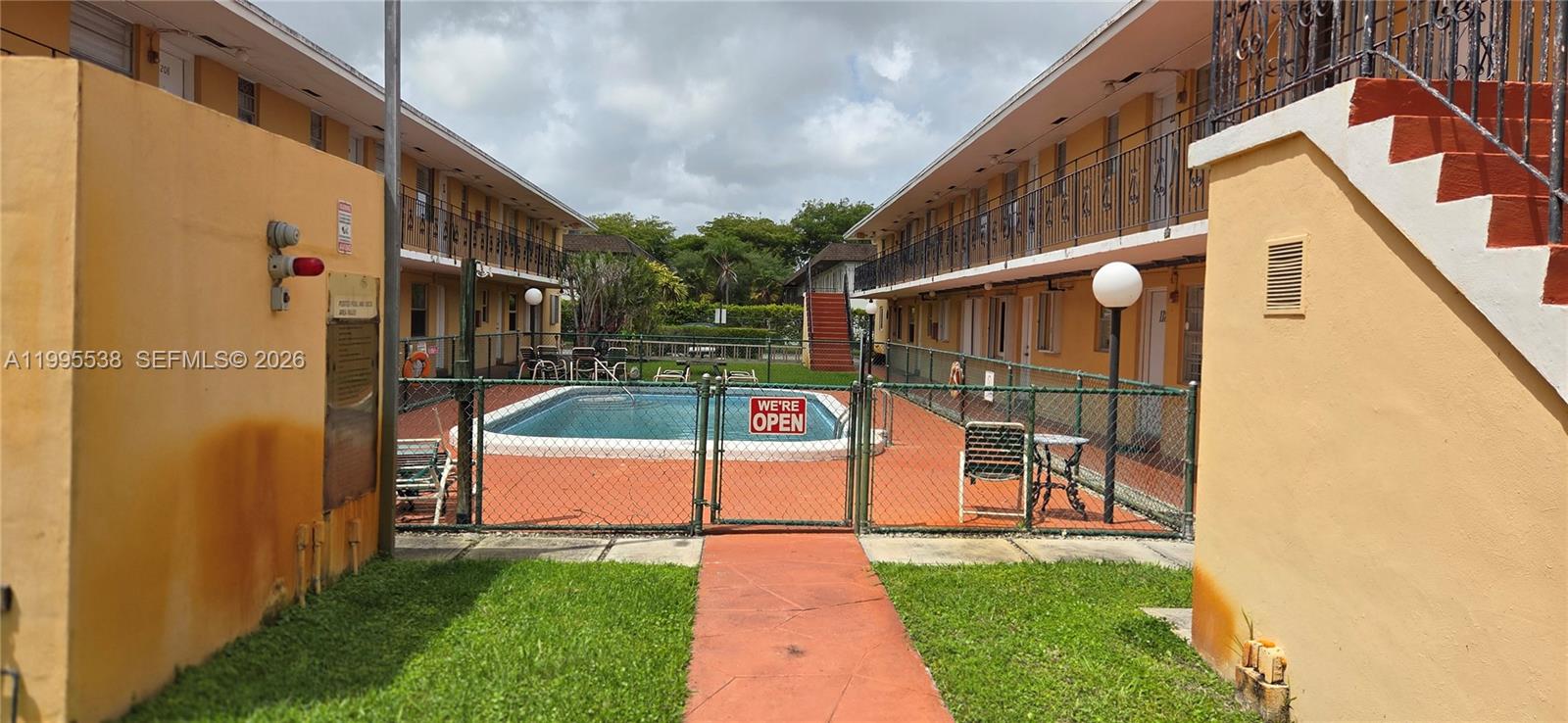 A swimming pool is enclosed by a chain-link fence between two yellow apartment buildings — 3800 SW 102nd Ave # 108, Miami FL 33165, MIAMI, FL