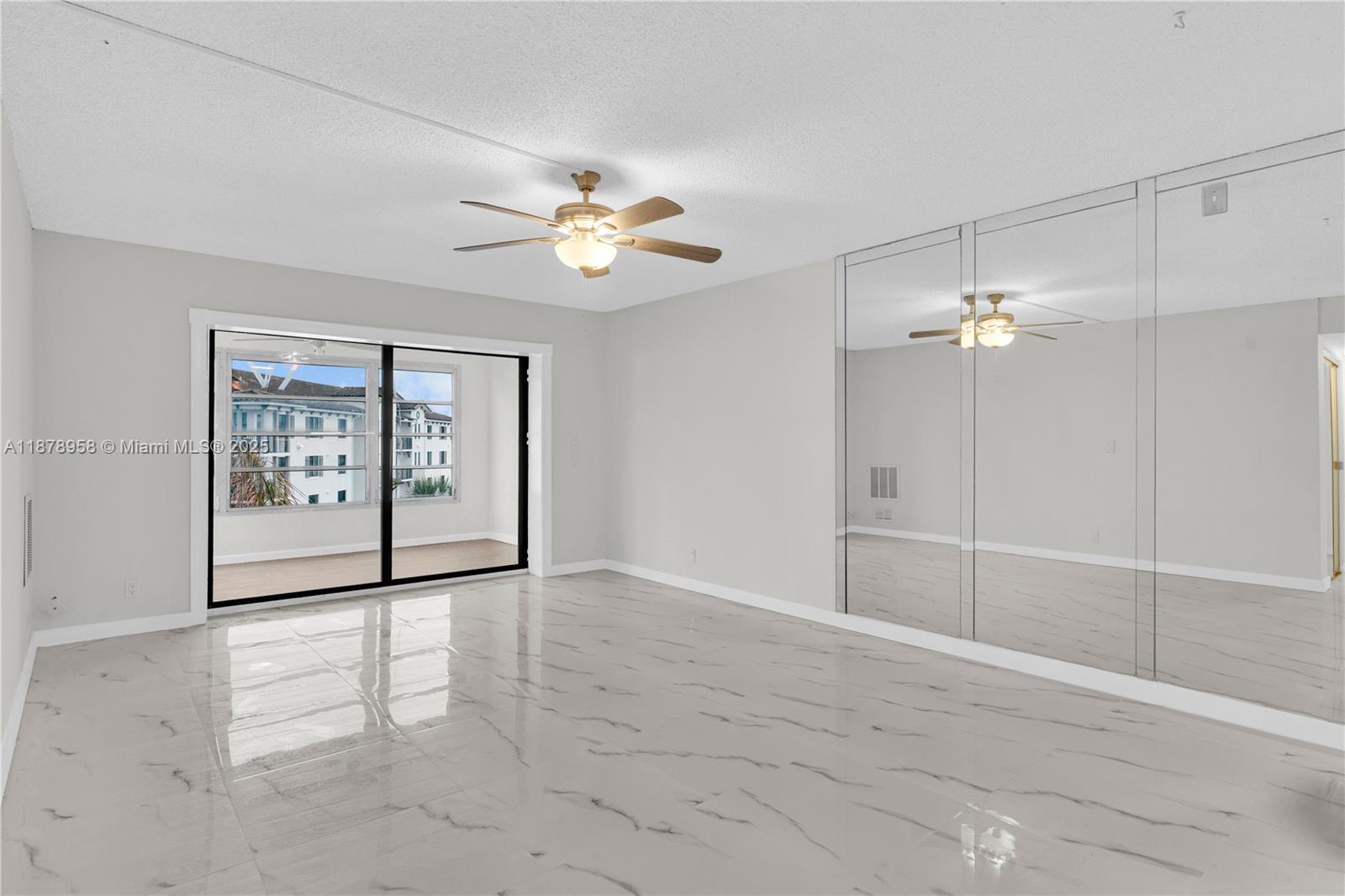 A room with white marble-look tile flooring, a ceiling fan, and a mirrored wall — 9355 SW 8th St # 425, Boca Raton FL 33428, BOCA RATON, FL