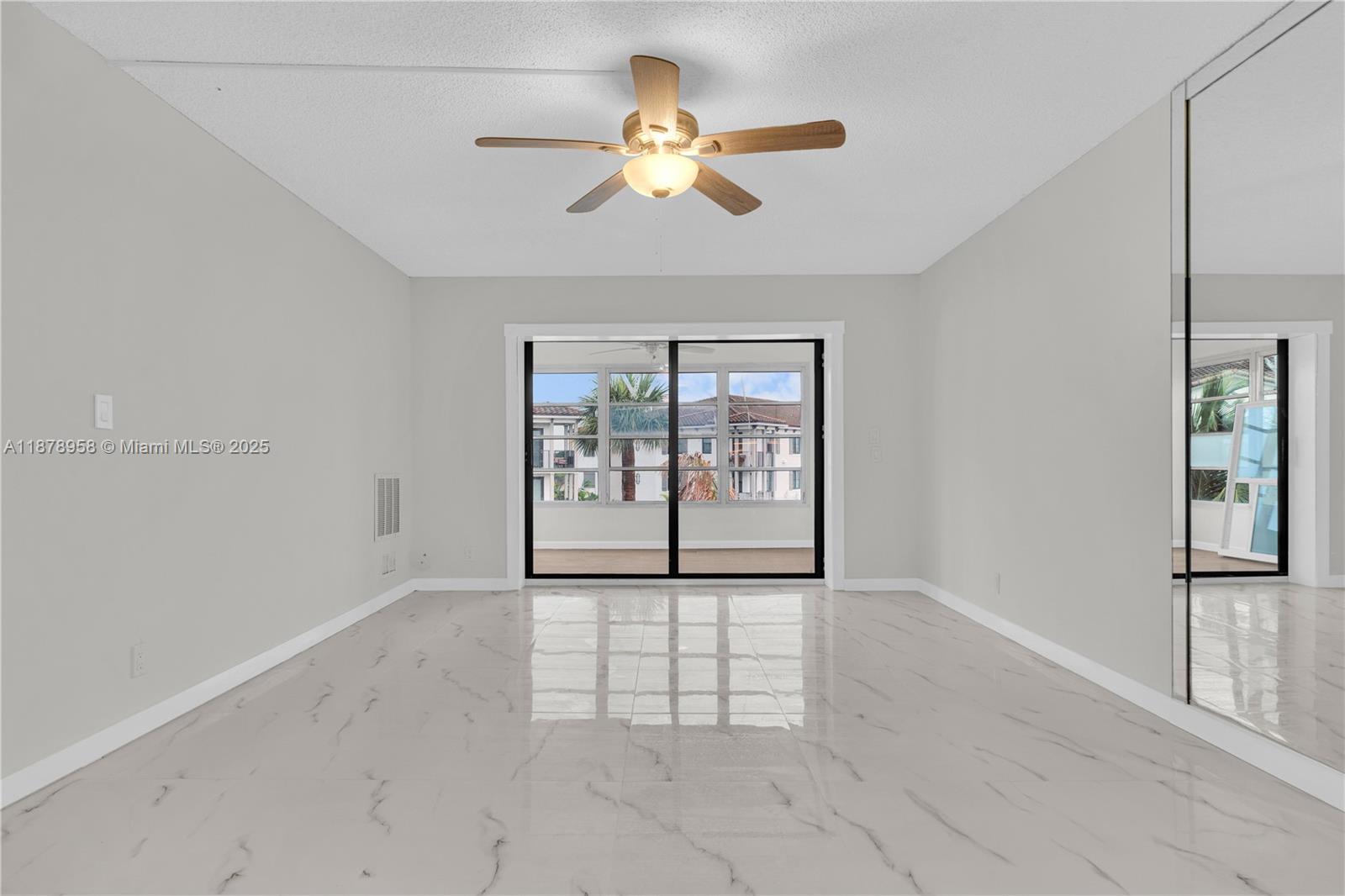 A bright room features white marble-look tile flooring, a ceiling fan, and sliding glass doors — 9355 SW 8th St # 425, Boca Raton FL 33428, BOCA RATON, FL