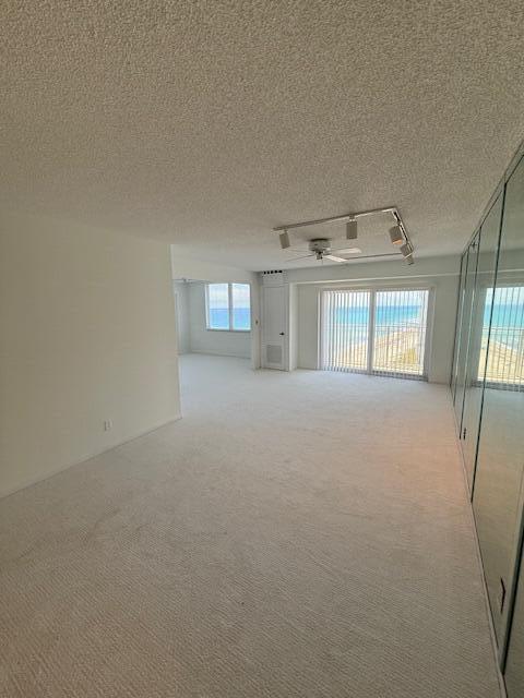 A spacious, carpeted living area features a ceiling fan, track lighting, and floor-to-ceiling balcony windows — 3215 S Ocean Boulevard # 911, Highland Beach FL 33487, HIGHLAND BEACH, FL