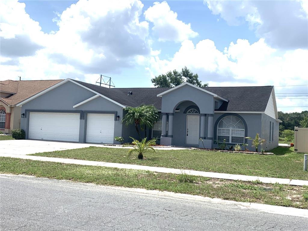 A gray single-story house with a two-car garage, arched entryway, and a dark shingled roof — 11513 ANDY DRIVE, RIVERVIEW, FL