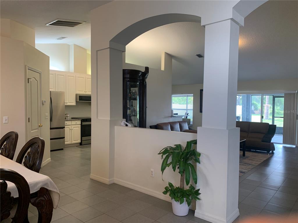 A view from a dining area looking into a kitchen and living room with tile floors — 11513 ANDY DRIVE, RIVERVIEW, FL