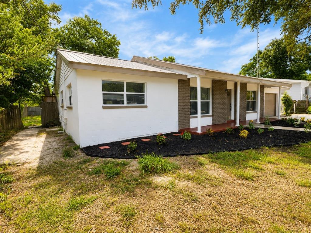 A single-story house with white walls, a metal roof, and a brick-accented front porch — 245 16TH STREET NE, WINTER HAVEN, FL