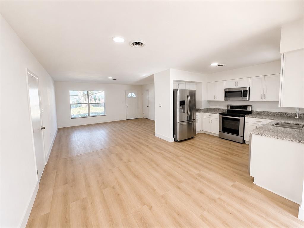An open-concept kitchen and living area feature light wood-look flooring and white cabinetry — 245 16TH STREET NE, WINTER HAVEN, FL
