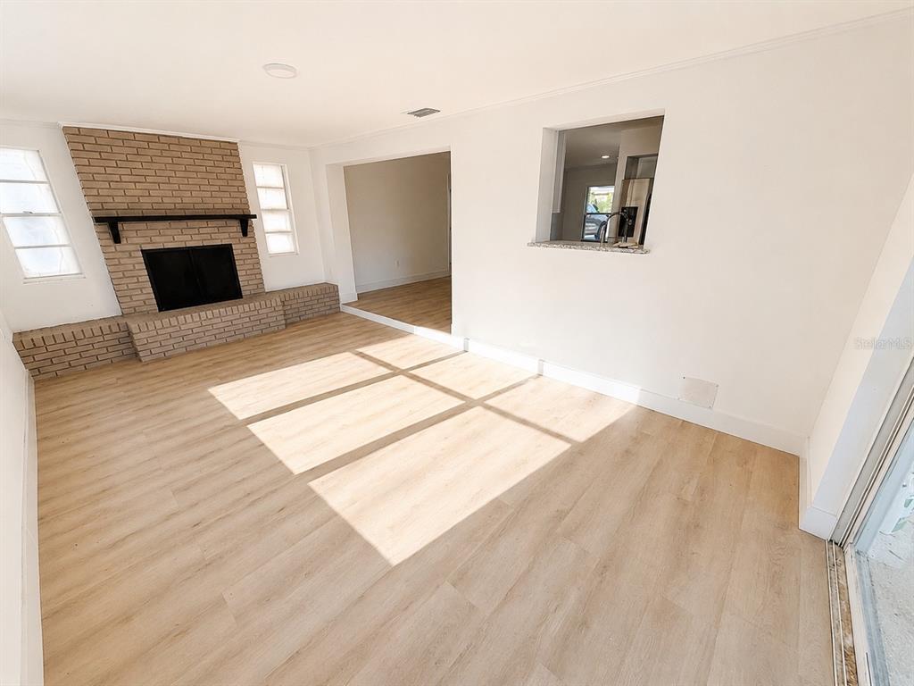 A living room features light wood-look flooring, a brick fireplace, and a kitchen pass-through window — 245 16TH STREET NE, WINTER HAVEN, FL