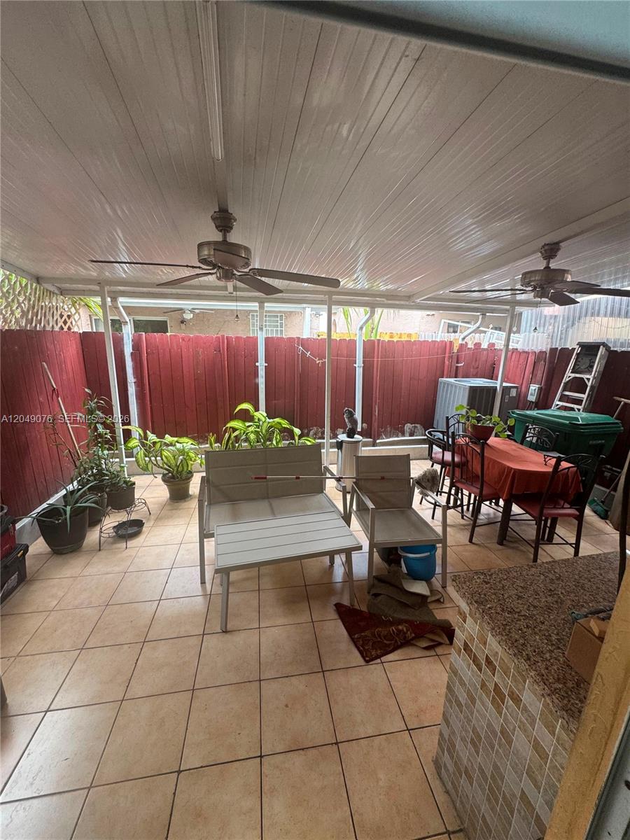A covered outdoor patio features tiled flooring, ceiling fans, and a red wooden fence — 8743 NW 106th Ln # 8743, Hialeah Gardens FL 33018, HIALEAH GARDENS, FL
