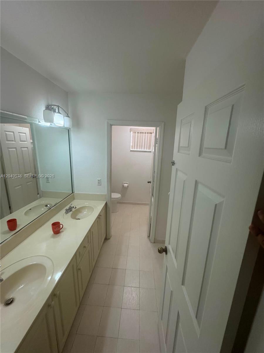 A bathroom features a double vanity with a large mirror and a separate toilet area — 8743 NW 106th Ln # 8743, Hialeah Gardens FL 33018, HIALEAH GARDENS, FL