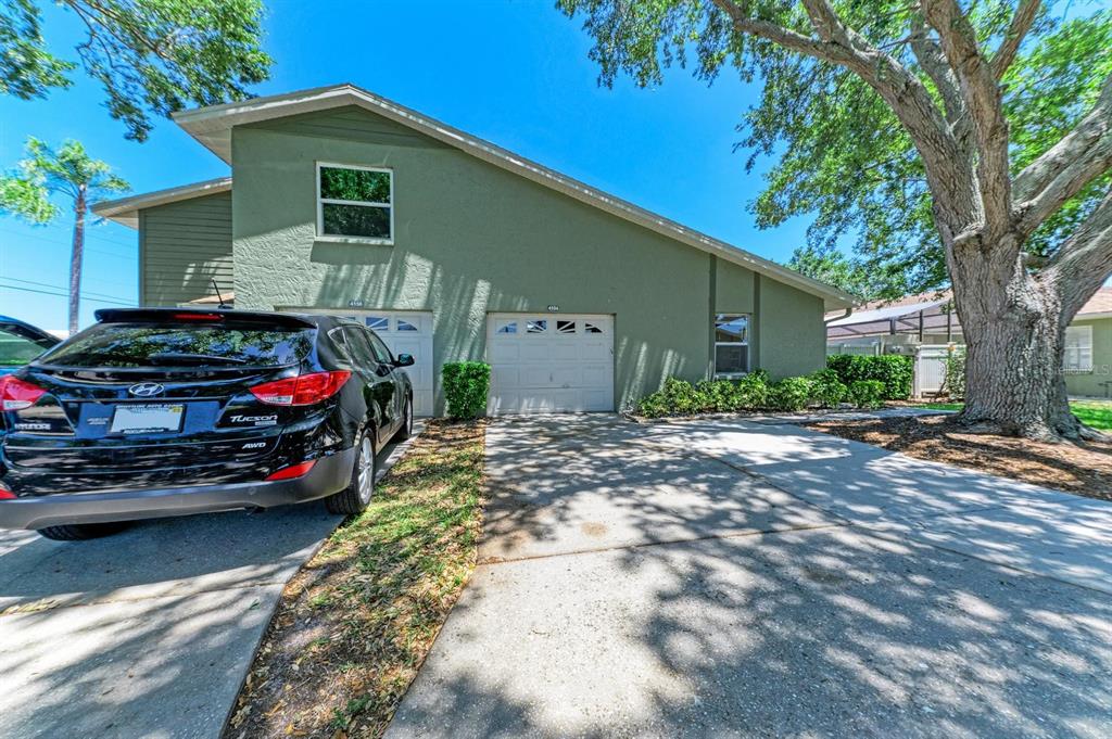 A green two-story duplex features two garage doors and a black SUV parked in front — 4154 CENTER POINTE CIRCLE UNIT 57A, SARASOTA, FL