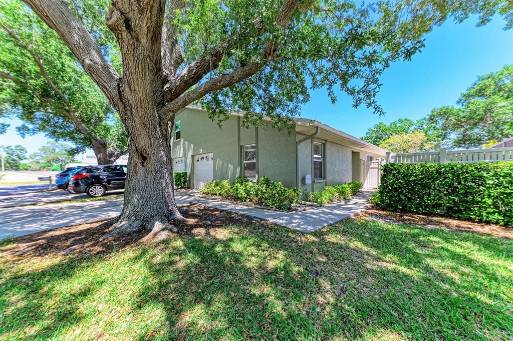 A large tree shades the exterior of a single-story house with a two-car garage — 4154 CENTER POINTE CIRCLE UNIT 57A, SARASOTA, FL