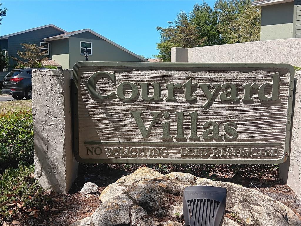 A sign for Courtyard Villas stands in front of a residential building and a car — 4154 CENTER POINTE CIRCLE UNIT 57A, SARASOTA, FL