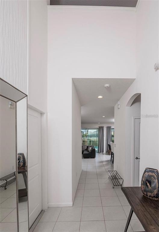 A tiled hallway leads from a foyer toward a living area with large windows — 2659 CALISTOGA AVENUE, KISSIMMEE, FL