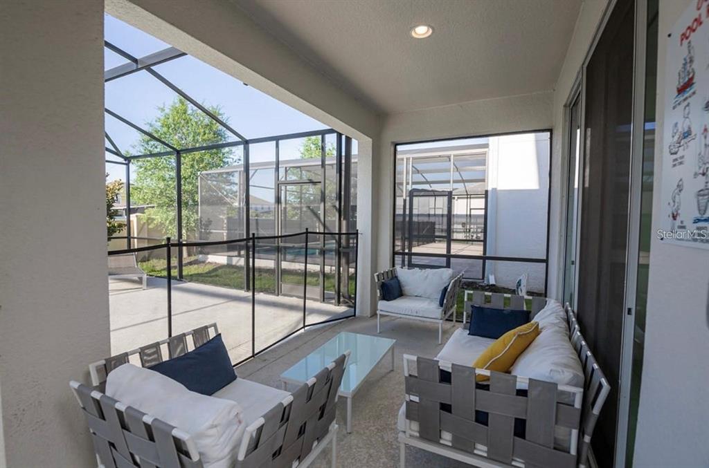 A covered patio features outdoor furniture, a safety fence, and a screened-in pool area — 2659 CALISTOGA AVENUE, KISSIMMEE, FL