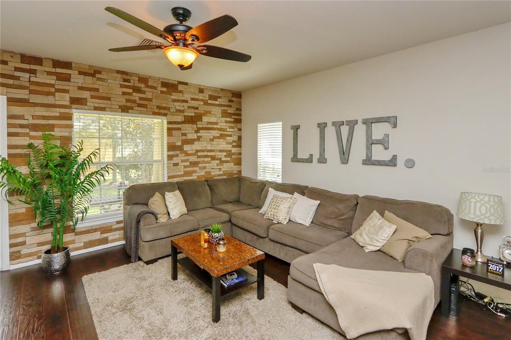 A living room features a stone accent wall, a sectional sofa, and a ceiling fan — 4724 SOMERSET HILL LANE, RIVERVIEW, FL