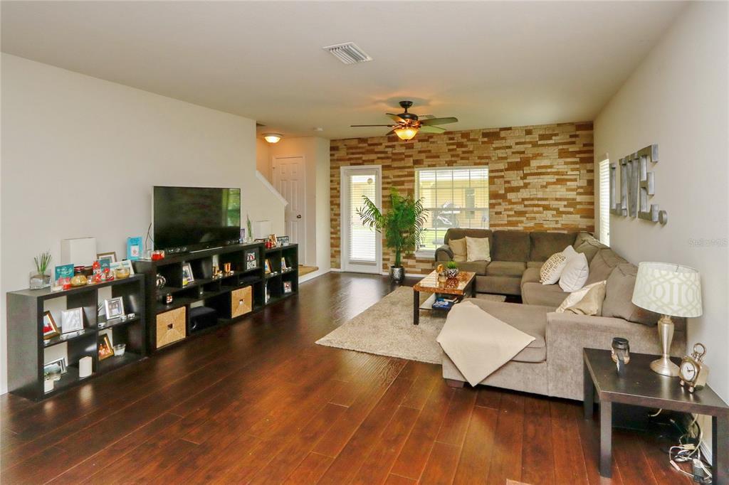 A living room features dark wood floors, a stone accent wall, and a sectional sofa — 4724 SOMERSET HILL LANE, RIVERVIEW, FL