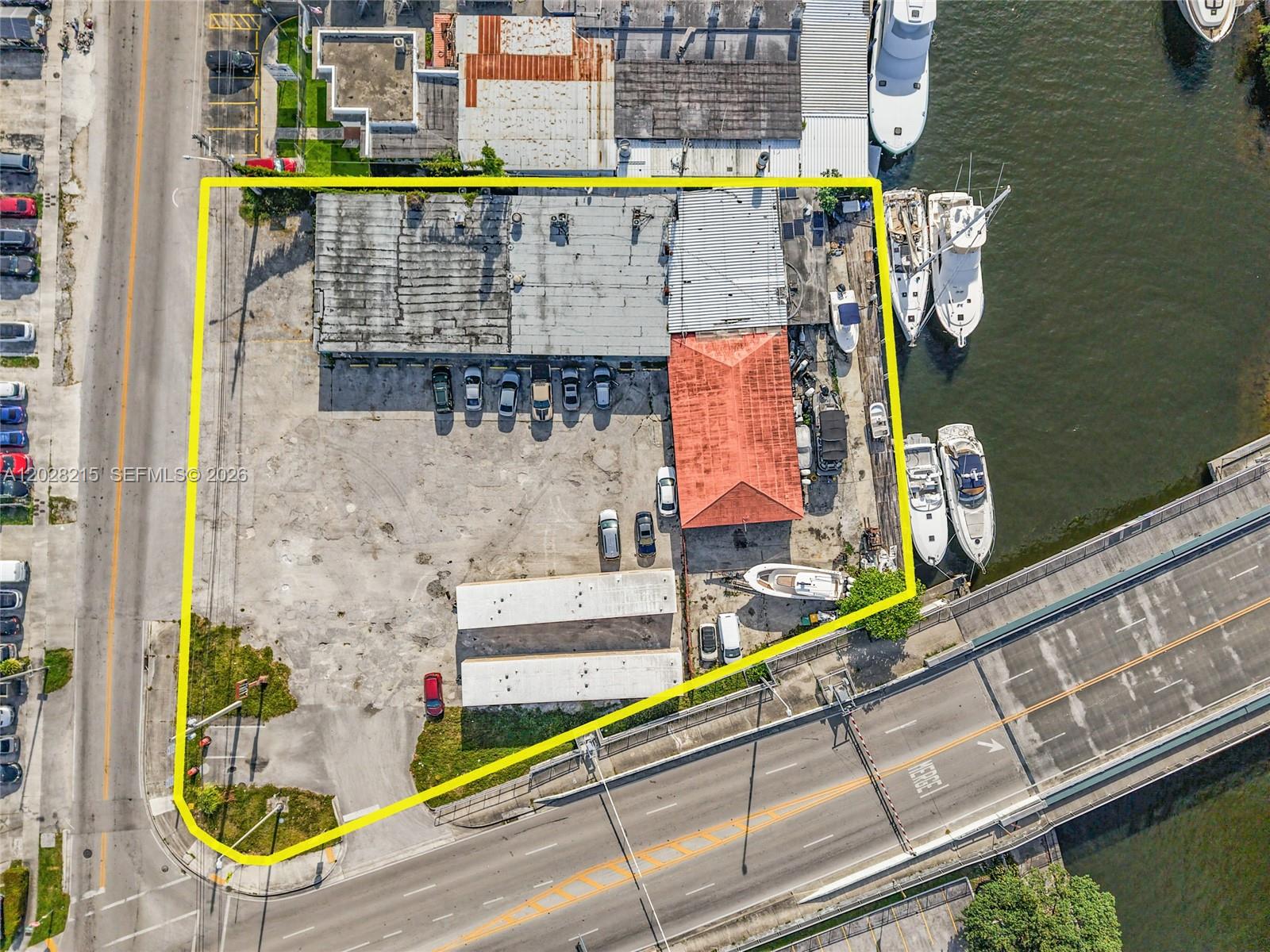 An aerial view shows a commercial property with a warehouse, parking lot, and boat slips — 3066 NW River Dr, Miami FL 33142, MIAMI, FL