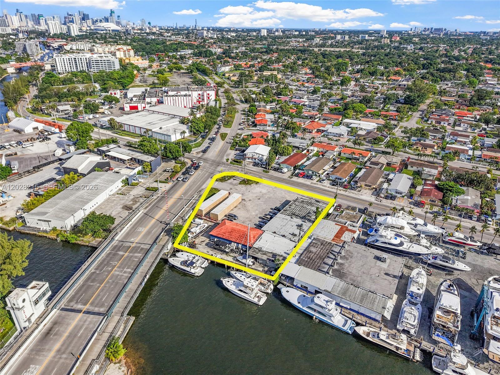 An aerial view shows a waterfront commercial property outlined in yellow next to a bridge — 3066 NW River Dr, Miami FL 33142, MIAMI, FL