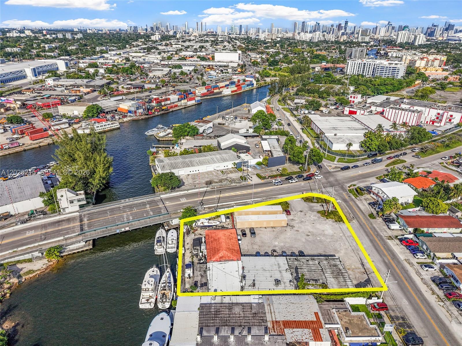 An aerial view shows a waterfront commercial lot outlined in yellow near a bridge — 3066 NW River Dr, Miami FL 33142, MIAMI, FL