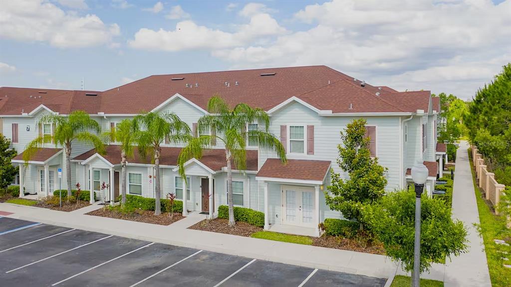 A multi-unit residential building with light siding, a brown roof, and palm trees in front — 3201 GOLD LANE, KISSIMMEE, FL