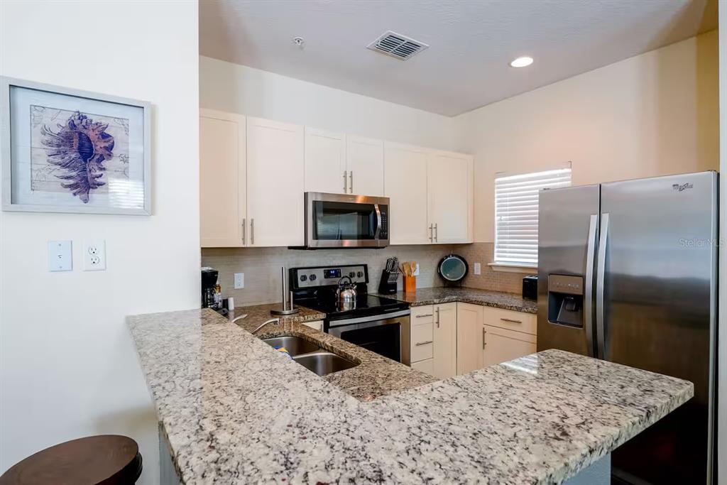 A kitchen features granite countertops, stainless steel appliances, and white cabinetry — 3201 GOLD LANE, KISSIMMEE, FL