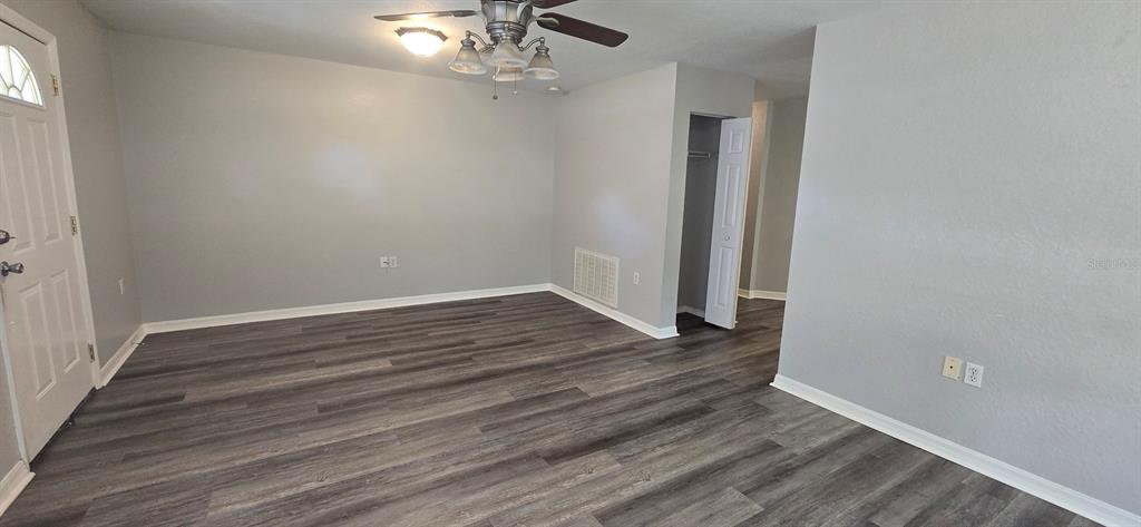 An empty room features gray walls, wood-look flooring, a ceiling fan, and a closet — 2605 NE 22ND AVENUE, OCALA, FL