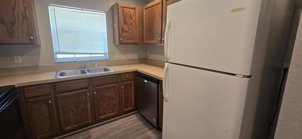 A kitchen features wood cabinets, a stainless steel dishwasher, a white refrigerator, and laminate countertops — 2605 NE 22ND AVENUE, OCALA, FL