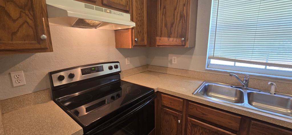 A kitchen features wood cabinets, a black electric range, a double sink, and laminate countertops — 2605 NE 22ND AVENUE, OCALA, FL