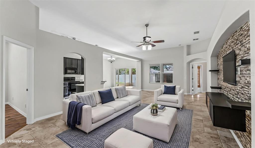 A living room with a stone accent wall, tile flooring, and a white sofa set — 248 TOWERVIEW DRIVE W, HAINES CITY, FL