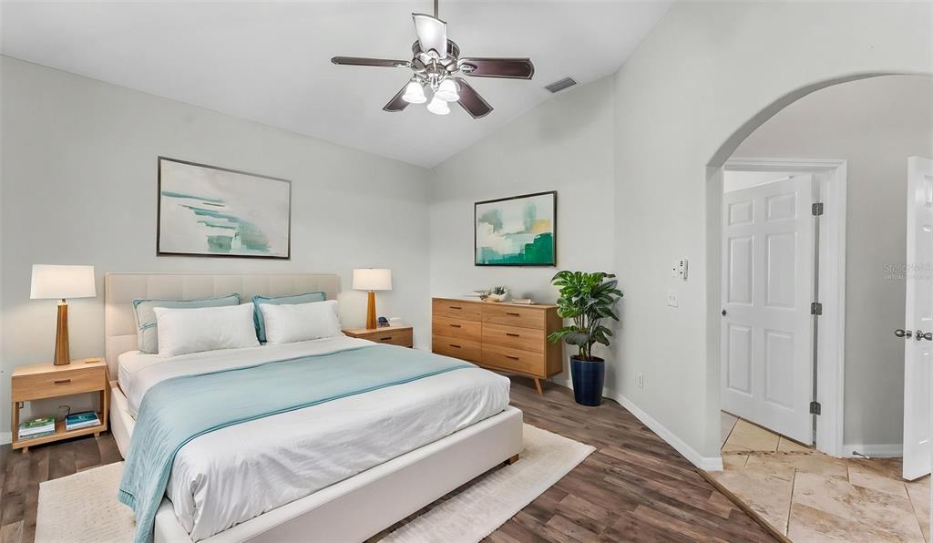 A bedroom features a bed, wooden dresser, ceiling fan, and light-colored walls with wood flooring — 248 TOWERVIEW DRIVE W, HAINES CITY, FL