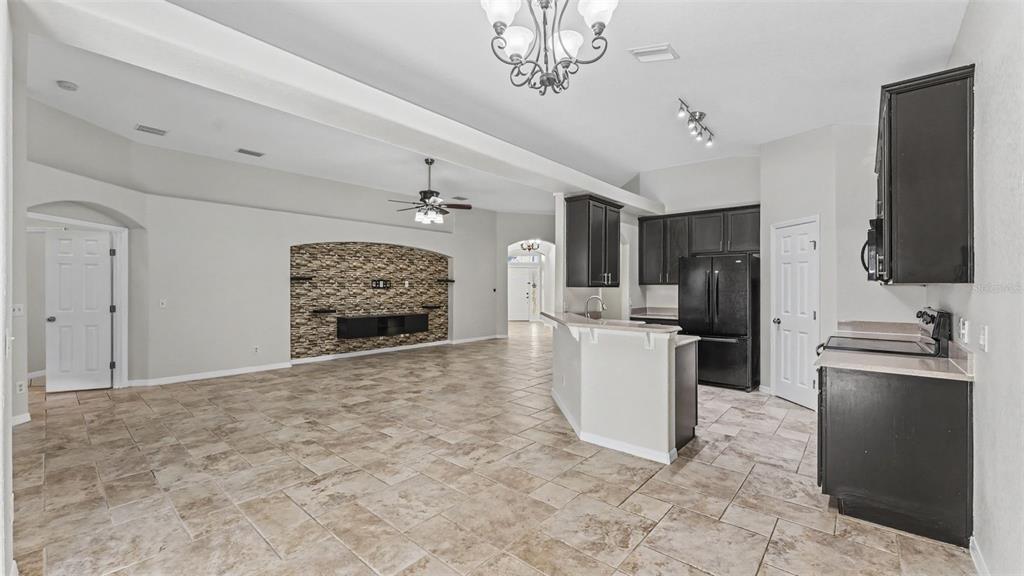 A kitchen with dark cabinets and a breakfast bar opens into a living area — 248 TOWERVIEW DRIVE W, HAINES CITY, FL