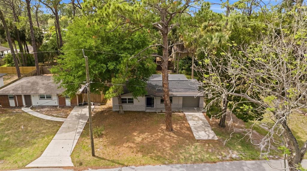 An aerial view shows two single-story houses with driveways and trees on a residential lot — 7151 PINEWOOD DRIVE, NEW PORT RICHEY, FL