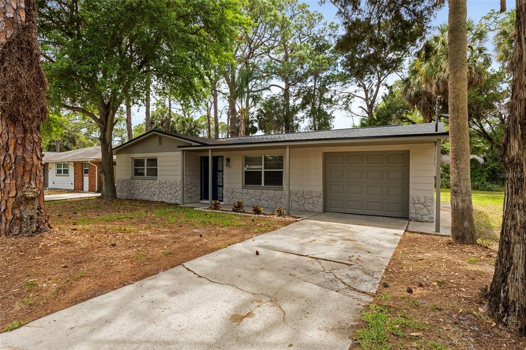 A single-story house with a stone facade, beige siding, and an attached garage — 7151 PINEWOOD DRIVE, NEW PORT RICHEY, FL