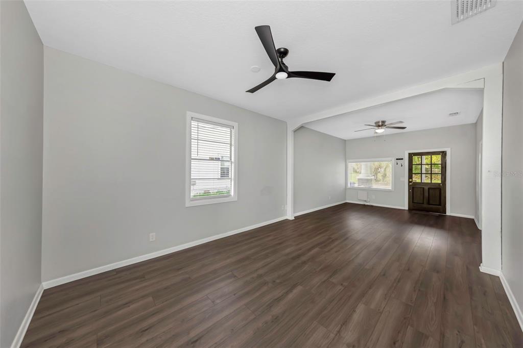 An interior view of a living room with gray walls, dark wood flooring, and ceiling fans — 2613 N 21ST STREET, TAMPA, FL