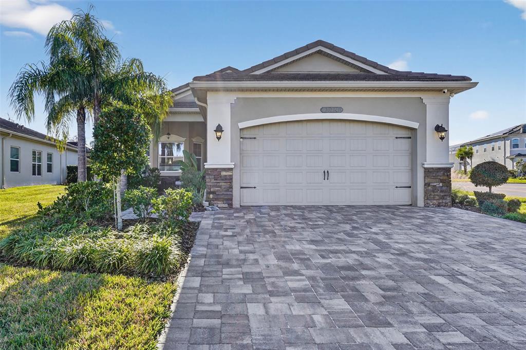 A single-story house with a paved driveway, stone accents, and a two-car garage — 30724 LINDENTREE DRIVE, WESLEY CHAPEL, FL