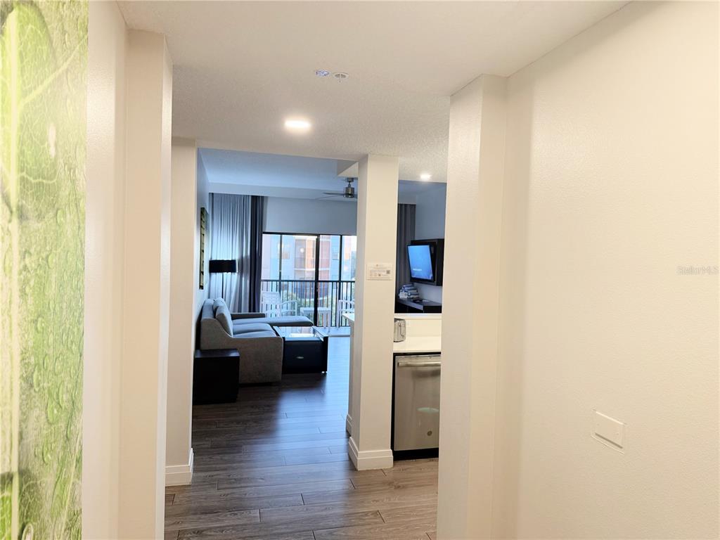 A hallway leads to a living room with a balcony and an adjacent kitchen area — 14501 GROVE RESORT AVENUE UNIT 2536, WINTER GARDEN, FL