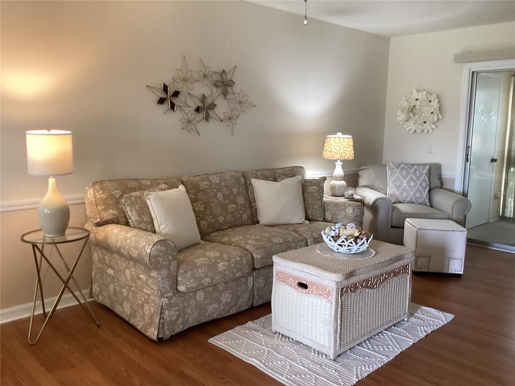 A living room features a floral sofa, a wicker coffee table, and a matching armchair — 1250 S PINELLAS AVENUE UNIT 306, TARPON SPRINGS, FL